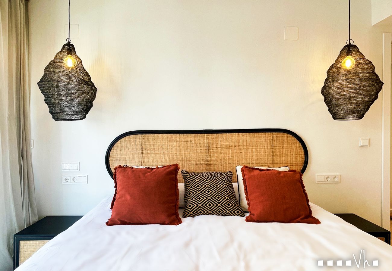 Master bedroom with King Size bed, rattan headboard and artisan lamps in luxury apartment Moraira